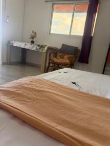 a bed in a room with a table and a window at Résidence Maeva in Mtsamboro