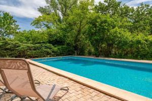 a blue swimming pool with a chair at Le Mas Perdu Gîte Studio Parme in Saint-Christol-lès-Alès