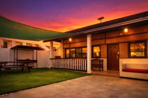 a house with a sunset in the background at Mayumi Lodge in Puerto Princesa City