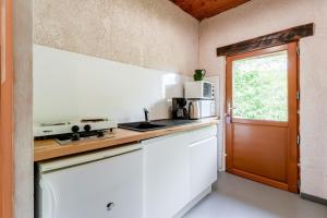 a kitchen with a stove and a microwave and a door at Le Mas Perdu Gîte Studio Parme in Saint-Christol-lès-Alès