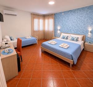 a hotel room with two beds and a desk at Donna Ginevra Rooms - A soli 300m dalla Spiaggia in Lido Marini