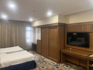 a hotel room with a bed and a flat screen tv at Oriental Residence in Dammam
