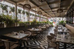 a restaurant with tables and chairs and potted plants at Mastiff Hotel Hinjawadi Pune in Pune
