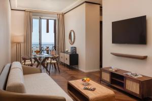 a living room with a couch and a television on a wall at UNA Hotels Capotaormina in Taormina