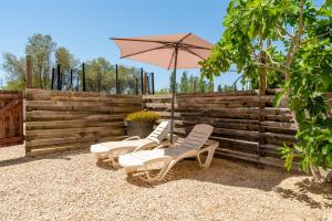 three chairs and an umbrella in front of a fence at Mas Delorme 1 in Arles