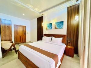 a bedroom with a large white bed and a desk at Secret Gem in Arugam Bay