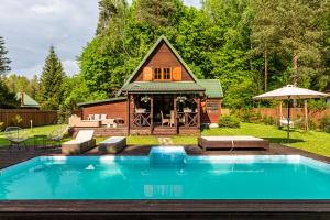 a house with a pool in front of a cabin at Leśny Raj in Świętajno