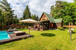 a backyard with a pool and an umbrella and a house at Leśny Raj in Świętajno