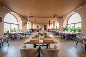 a restaurant with tables and chairs and large windows at Tree of Life Ganga Dwar, Haridwar in Haridwār