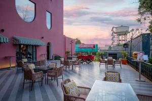 a patio with tables and chairs and a pink building at Tree of Life Ganga Dwar, Haridwar in Haridwār