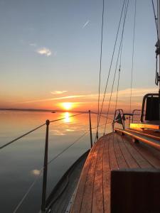 a boat with the sun setting on the water at Geschmackvolles Zimmer in Steinhude in Wunstorf +4 photos