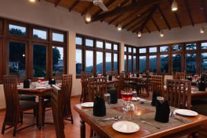 a restaurant with wooden tables and chairs and windows at Oak Ray Serene Garden Hotel in Kandy