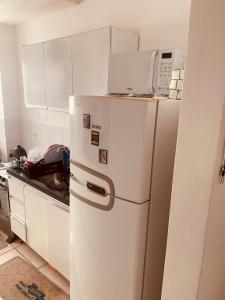 a white refrigerator with a microwave on top of it at Acalmaria Residence in Macaé