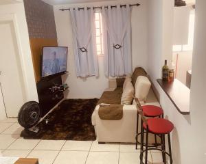 a living room with a couch and a tv at Acalmaria Residence in Macaé