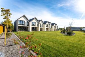 a large house with a green lawn in front of it at BURSZTYN - BERNSTEIN SPA & Wellness in Dąbki