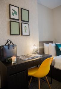un escritorio en una habitación de hotel con una silla amarilla y una cama en Wherstead House, en Ipswich