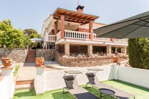 a house with a patio with chairs and an umbrella at Villa Toro in Maçanet de la Selva
