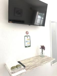 a tv hanging on a wall with a wooden shelf at Casa da Calma - GUESTHOUSE in Alandroal