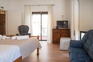 a bedroom with a bed and a couch and a tv at Estoril Guest Palace in Estoril