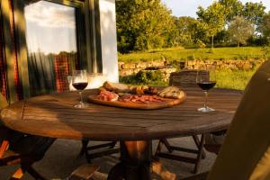 a wooden table with a pizza and two glasses of wine at La Bergerie de Losse in Traize