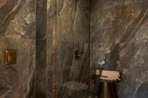 a bathroom with a shower with a sink and a table at PERATZADA central suite in Argostoli