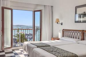 a hotel room with two beds and a balcony at Hotel Sis Pins in Port de Pollensa