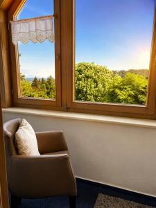 ein Stuhl in einem Raum mit zwei Fenstern in der Unterkunft Hotel Daheim in Gehlberg + 3 Fotos