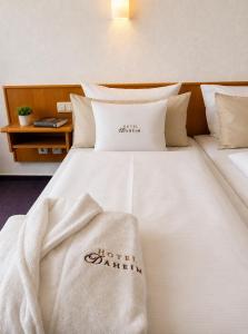 ein Hotelzimmer mit einem Bett mit weißen Laken und Kissen in der Unterkunft Hotel Daheim in Gehlberg
