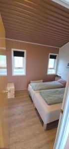 two beds in a room with two windows at Eaglerock guesthouse 2 in Kirkjubæjarklaustur