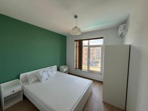 a bedroom with a white bed and a green wall at Апартамент Солана - Apartment Solana in Lozenets