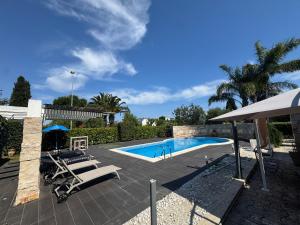 a swimming pool with two lounge chairs and an umbrella at Apulian Way in Torre Pelosa