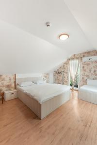 a white bedroom with a large bed and a wooden floor at Casa Diana Confort in Avrig