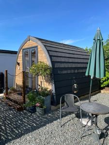 a small house with a table and an umbrella at Fat Pete's Pod in Norwich