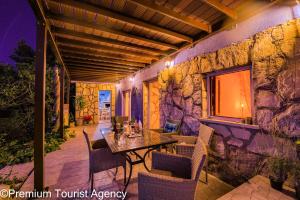 a patio with a table and chairs and a stone wall at Hidden Beach Villa Biankura in Smokvica