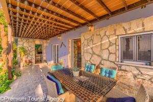 a patio with a table and chairs and a stone wall at Hidden Beach Villa Biankura in Smokvica