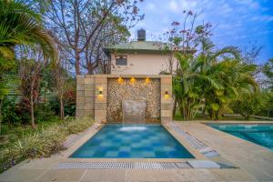 a swimming pool in front of a house at The Corbett Greens- A Wild Resort Muhaan in Tota Ām