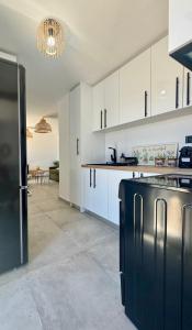 a kitchen with white cabinets and a black refrigerator at Salty Rock - Kythnos Suite in Kithnos