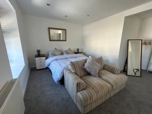 a bedroom with a couch and a bed and a mirror at New Drovers in Llanelli