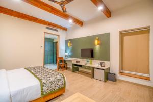 a bedroom with a bed and a desk and a television at The Corbett Greens- A Wild Resort Muhaan in Tota Ām