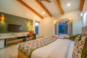 a bedroom with a bed and a desk and a television at The Corbett Greens- A Wild Resort Muhaan in Tota Ām +85 photos