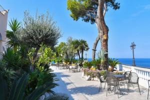 a patio with tables and chairs and the ocean at Hotel Terme Cristallo Palace in Casamicciola Terme