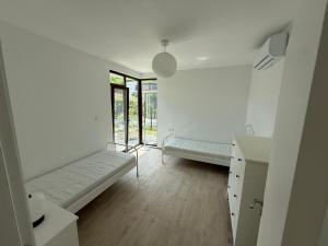 a white room with two beds and a window at Вила Фамилия - Villa Family in Lozenets