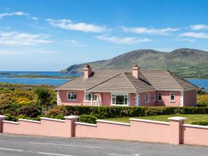 a pink house with the ocean in the background at Renard Lodge in Cahersiveen