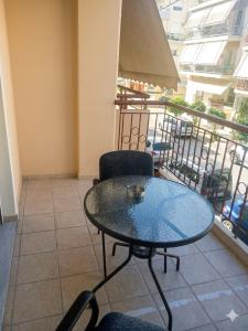 ein Glastisch und Stühle auf einem Balkon in der Unterkunft Elias Appartment in Volos