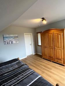 a bedroom with a bed and a wooden cabinet at Wohnung Ton Strand in Fehmarn