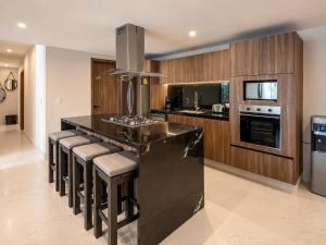 a kitchen with a black island with bar stools at Luxury Retreat in Puerto Cancun with Rooftop Pool in Cancún