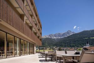 a balcony with tables and chairs and mountains at AVES Hotel Savognin in Savognin