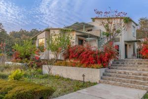 a house with red flowers in front of it at The Corbett Greens- A Wild Resort Muhaan in Tota Ām