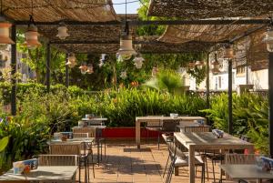 an outdoor patio with tables and chairs and plants at AQUA Hotel Bertran Park in Lloret de Mar