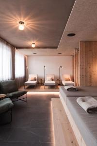 a room with two beds and a couch and chairs at MyLiving - Hotel B&B by Majestic Resorts Dolomites in San Lorenzo di Sebato